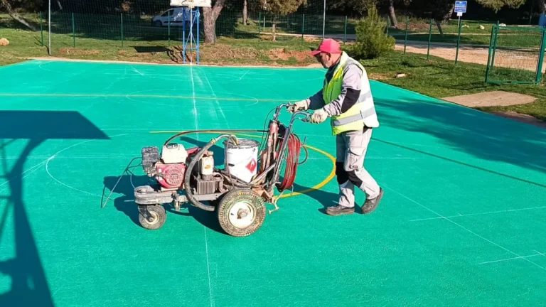 Djelatnik tvrtke LIČILAC d.o.o. aplicira zeleni premaz na površinu igrališta.