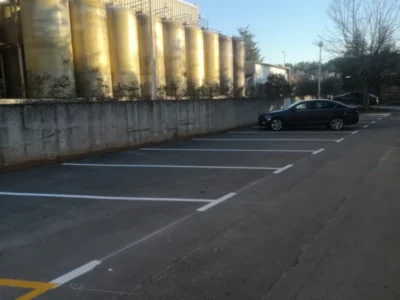 Iscrtana bijela parkirna mjesta uz betonski zid