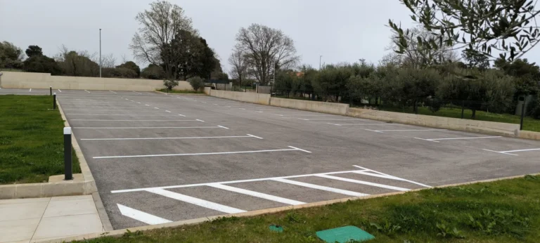 Svježe iscrtane bijele parkirne linije na novom asfaltu parkirališta Del Mar Emotion u Ližnjanu.