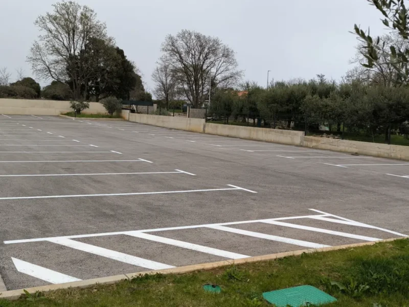 Svježe iscrtane bijele parkirne linije na novom asfaltu parkirališta Del Mar Emotion u Ližnjanu.
