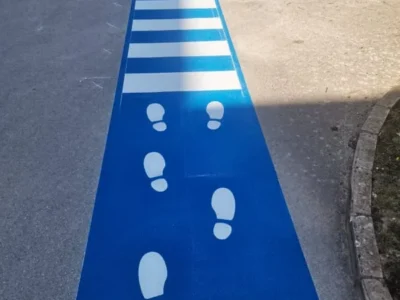 Detalj horizontalne signalizacije s bijelim otiscima stopala za sigurno usmjeravanje djece.