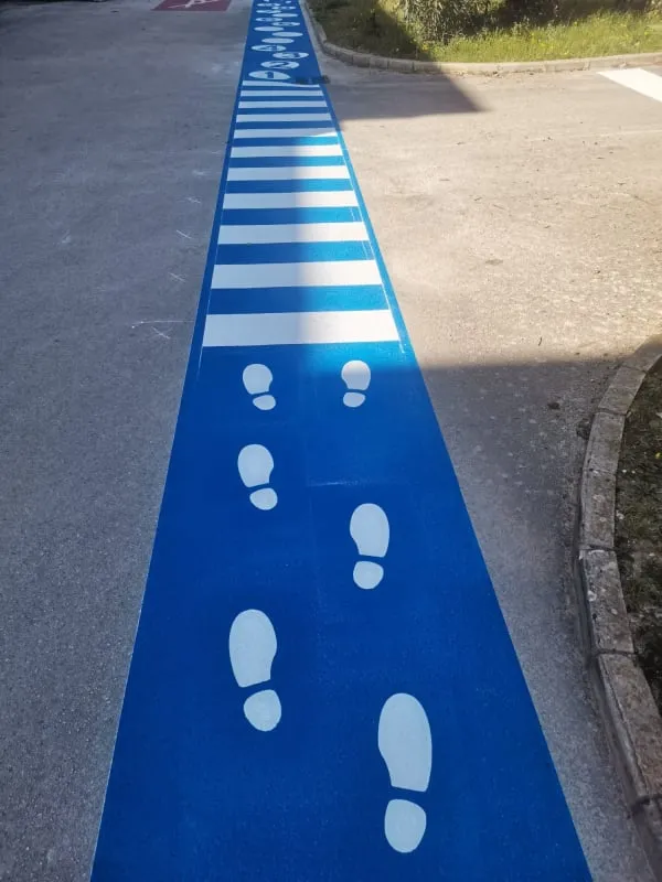 Detalj horizontalne signalizacije s bijelim otiscima stopala za sigurno usmjeravanje djece.