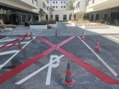Crvena horizontalna signalizacija koja označava zonu zabranjenog parkiranja s bijelim prekriženim linijama