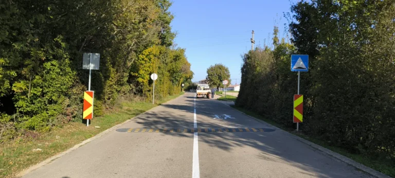 Široki prikaz prometnice s ležećim policajcem i znakovima upozorenja