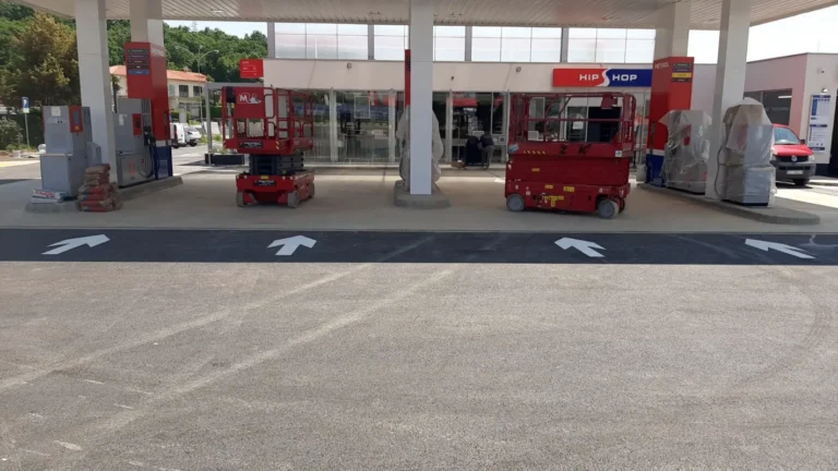 Bijele strelice iscrtane na prometnim trakama neposredno uz agregate za točenje goriva.