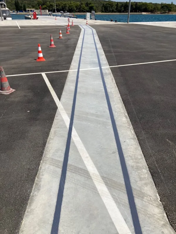 Duge paralelne linije iscrtane na šetnici uz more u Marini Polesana