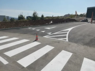 Iscrtan bijeli pješački prijelaz i strelice za usmjeravanje prometa na novom asfaltu poslovnog objekta u Labinu
