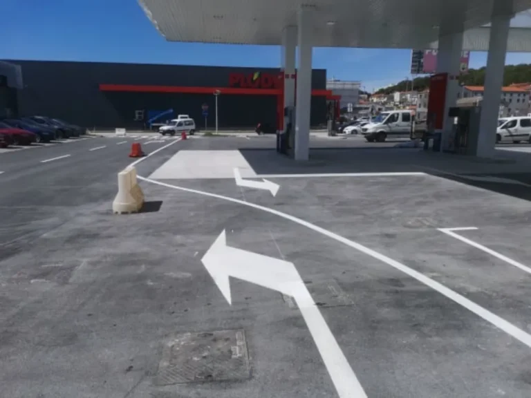 Iscrtane bijele strelice za usmjeravanje prometa na izlazu s benzinske postaje