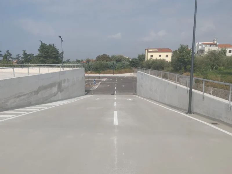 Ulazna rampa parkirne kuće u Poreču s precizno iscrtanim bijelim linijama i strelicama za usmjeravanje prometa.