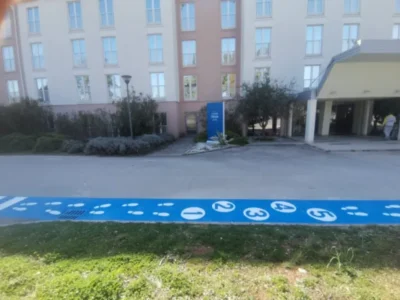 Plava pješačka staza s bijelim stopama i brojevima ispred dječjeg vrtića u Poreču.