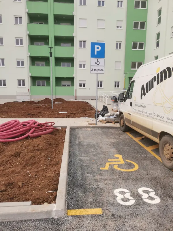 Iscrtana invalidska parkirališna mjesta žutom bojom i postavljen prometni znak za osobe s invaliditetom na APN stanovima u Umagu.