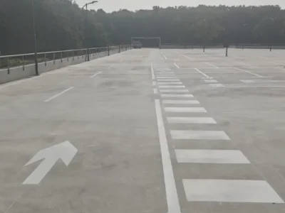 Prostrana krovna etaža parkirne kuće s jasno označenim parkirnim mjestima i pješačkim koridorima.
