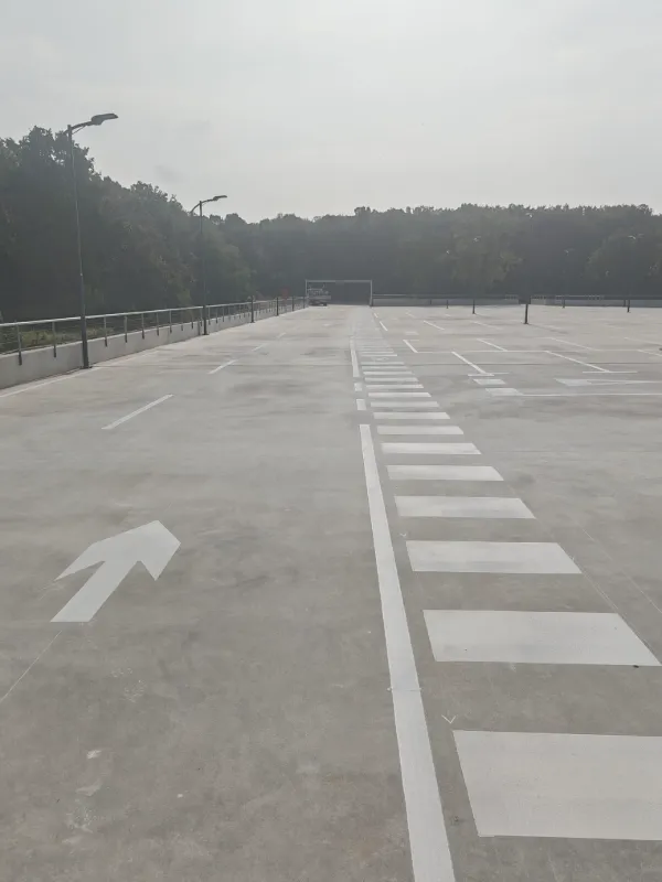 Prostrana krovna etaža parkirne kuće s jasno označenim parkirnim mjestima i pješačkim koridorima.
