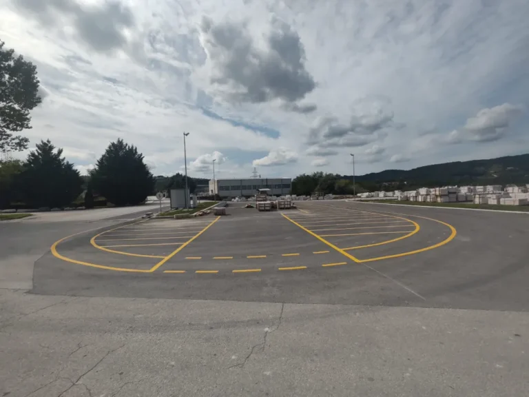 Prostrano industrijsko dvorište s precizno iscrtanim žutim linijama za parkiranje teretnih vozila u Pazinu.