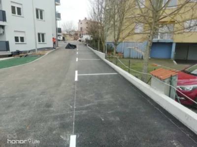 Iscrtane standardne bijele linije za parkirna mjesta na novom asfaltu uz stambenu zgradu