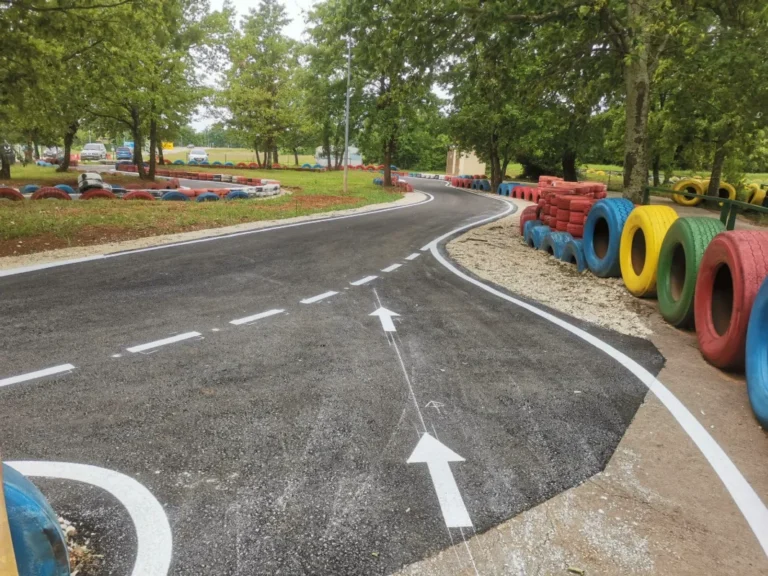 Bijele strelice za usmjeravanje i rubne linije iscrtane na asfaltu karting staze u Poreču.