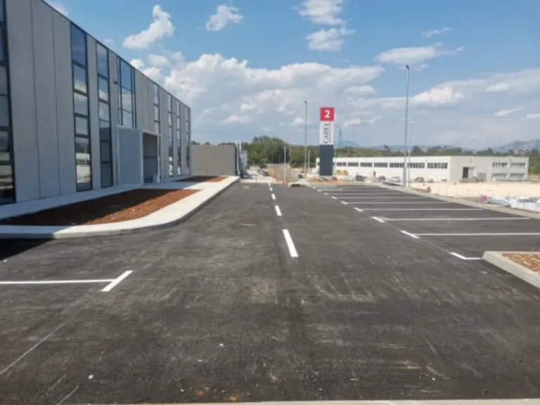 Dugačak niz iscrtanih parkirnih mjesta s jasnom horizontalnom signalizacijom na novom asfaltu