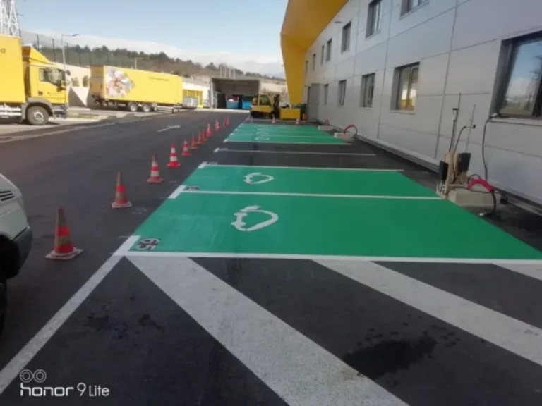 Iscrtane linije i simboli električnih automobila na zelenoj površini parkirališta.