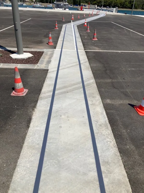 Svježe iscrtane tamno sive linije 2K PUR bojom na betonskoj površini u marini Polesana