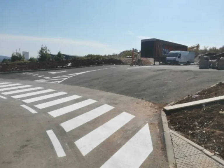 Široki pješački prijelaz i prometne oznake na svježe asfaltiranoj površini poslovnog kruga