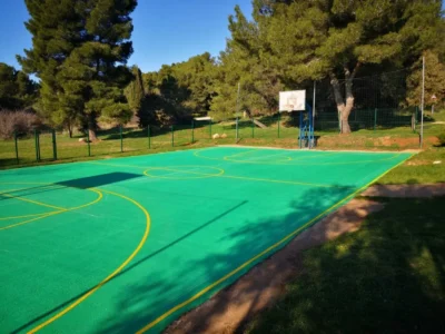 Svježe obojano zeleno sportsko igralište s iscrtanim žutim linijama za košarku u Pomeru.