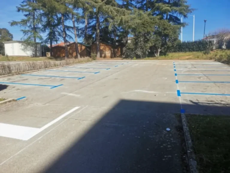 Obilježena parkirna mjesta plavim linijama na betonskoj podlozi pokraj vrtića.