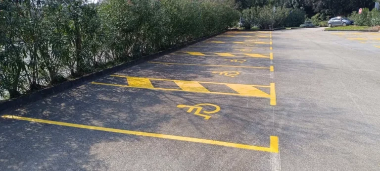 Detalj iscrtavanja žutih linija i piktograma za invalidska mjesta na hotelskom parkiralištu.