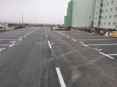 Veliko parkiralište s precizno iscrtanim bijelim linijama i brojevima parkirnih mjesta.