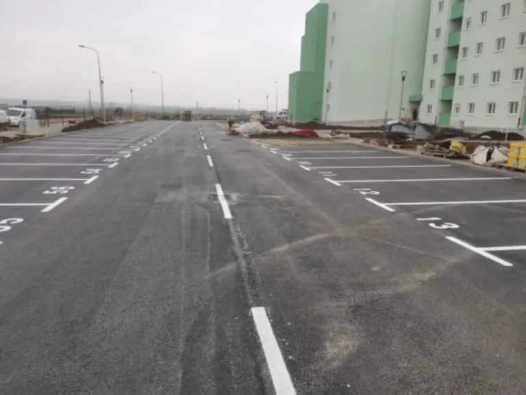Veliko parkiralište s precizno iscrtanim bijelim linijama i brojevima parkirnih mjesta.