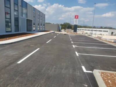 Svježe obojane bijele linije parkirnih mjesta ispred modernog poslovnog objekta