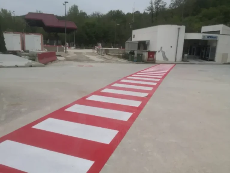 Dugi crveno-bijeli pješački prijelaz u industrijskoj zoni za sigurnost radnika
