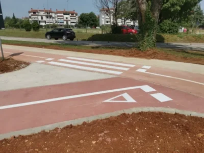 Iscrtan pješački prijelaz i oznake upozorenja na crvenoj podlozi biciklističke staze