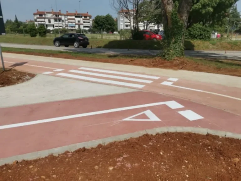 Iscrtan pješački prijelaz i oznake upozorenja na crvenoj podlozi biciklističke staze