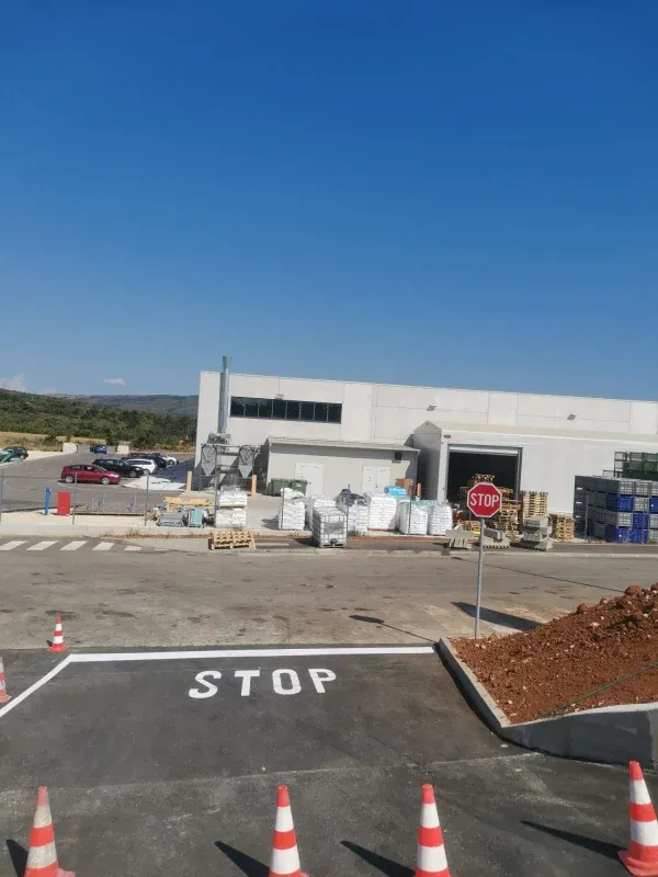 Veliki bijeli natpis STOP i zaustavna linija iscrtani na asfaltu ispred skladišnog prostora