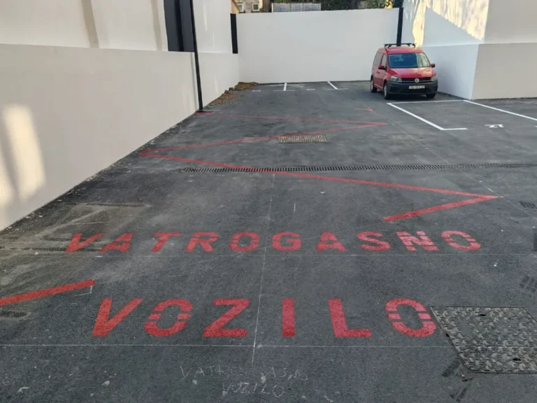 Veliki crveni natpis vatrogasno vozilo iscrtan na asfaltu stambenog parkirališta.