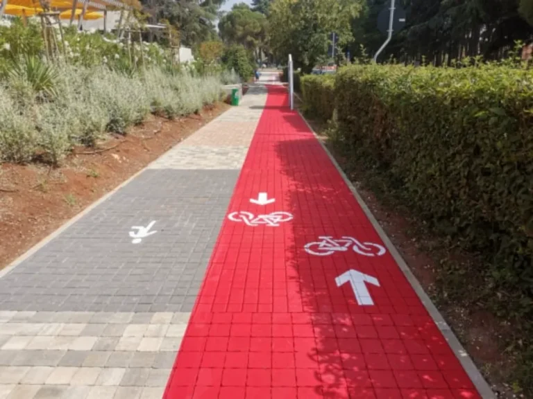 Bijele strelice i simboli koji usmjeravaju kretanje biciklista i pješaka na stazi