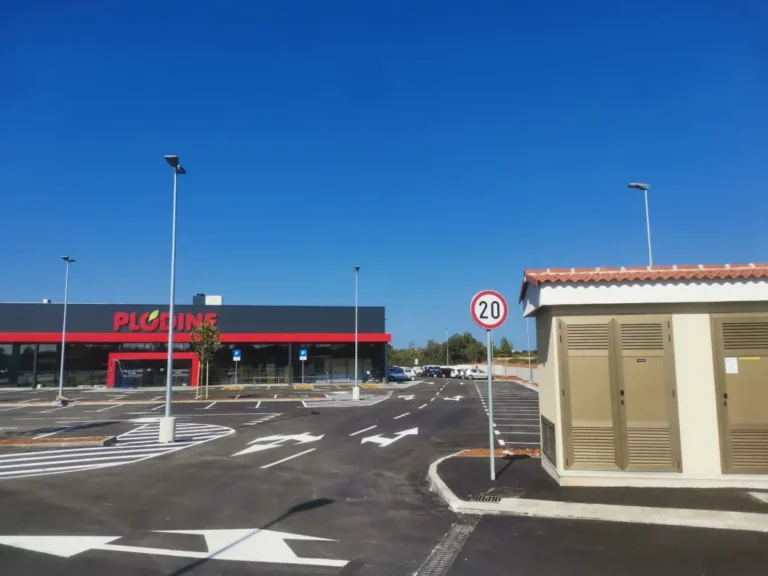 Obilježeno parkiralište s pješačkim prijelazom i vertikalnim znakom ograničenja brzine od 20 km na sat.