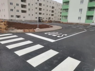 Iscrtan pješački prijelaz i oznaka STOP na asfaltu ispred novih stambenih zgrada u Umagu.