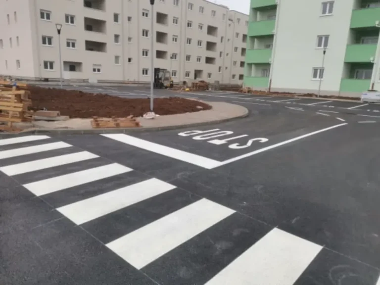 Iscrtan pješački prijelaz i oznaka STOP na asfaltu ispred novih stambenih zgrada u Umagu.