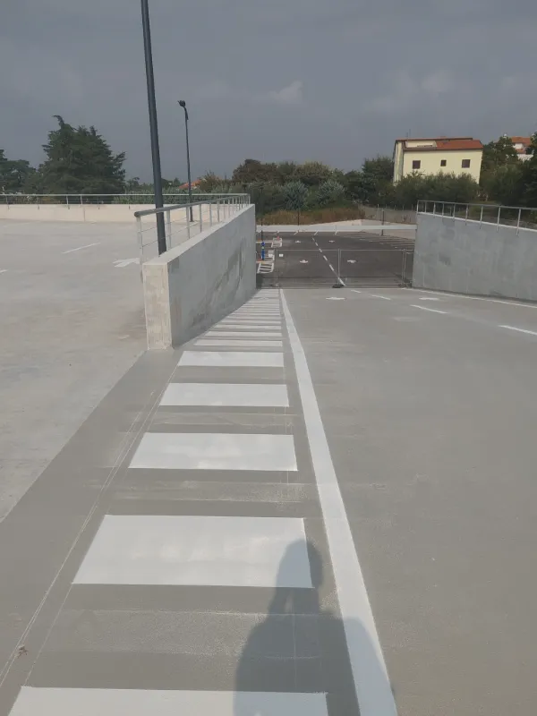 Iscrtan pješački prijelaz i rubne linije na kosoj rampi parkirališta za sigurnu komunikaciju pješaka.