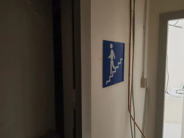 Plavi informativni znak za pješačke stepenice postavljen unutar objekta