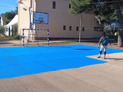 Radnik tvrtke LIČILAC d.o.o. nanosi plavi premaz na sportsko igralište u Banjolama