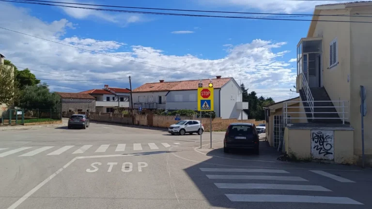 Raskrižje s postavljenim znakom STOP i oznakom za pješački prijelaz na fluorescentnoj podlozi