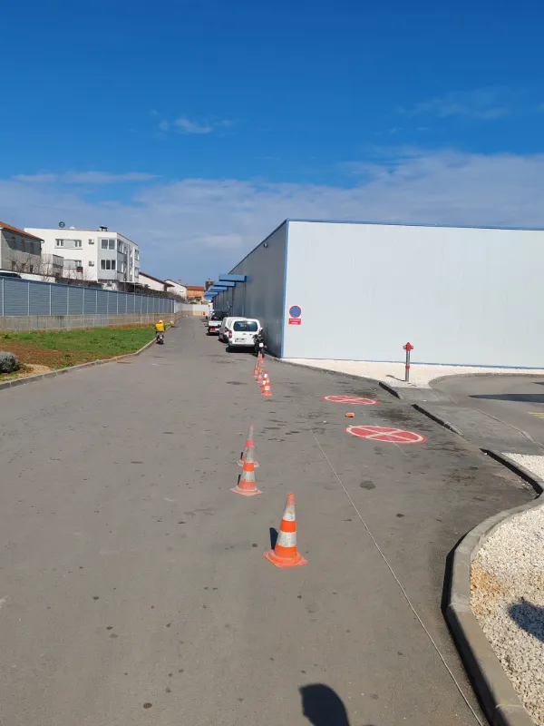 Prikaz iscrtanih crvenih oznaka zabrane parkiranja duž dostavne ceste trgovačkog centra.