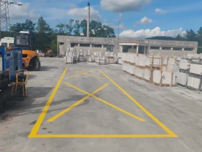 Žuta oznaka u obliku slova X na betonskoj podlozi koja upozorava na zabranu zaustavljanja i sigurnosnu zonu.