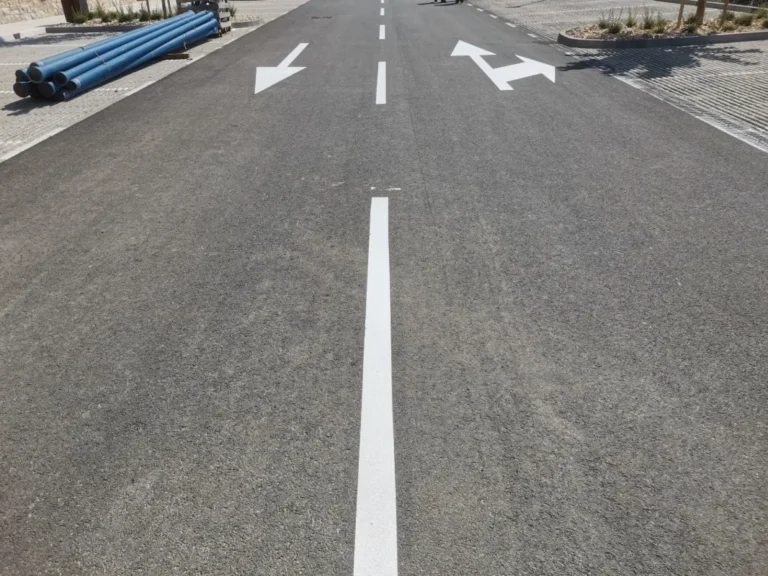 Dugačka isprekidana i puna bijela linija na svježe asfaltiranoj prometnici kompleksa.