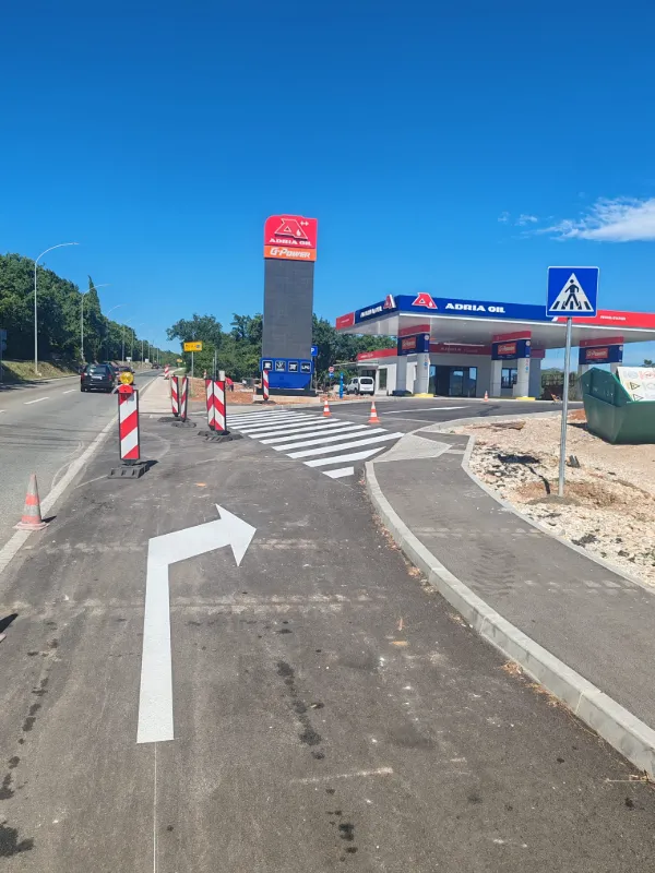 Bijela strelica za usmjeravanje prometa iscrtana na novom asfaltu benzinske postaje Adria Oil.