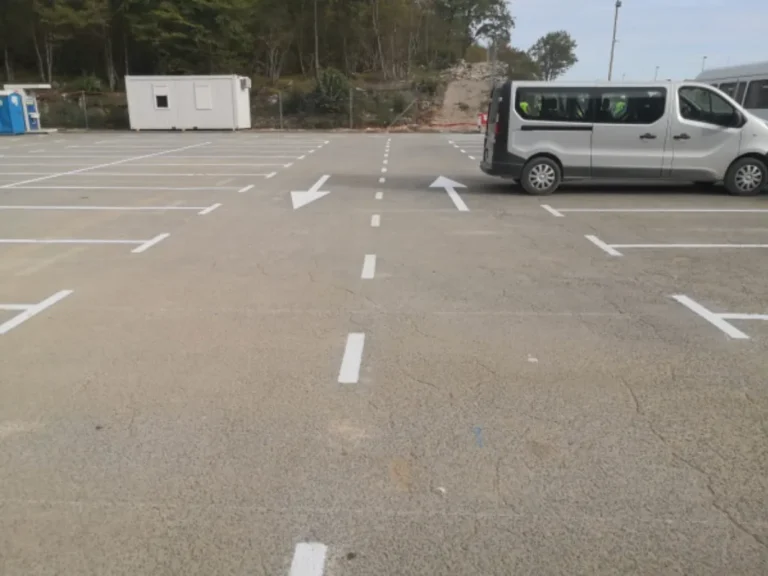 Bijele strelice na asfaltu koje označavaju smjer kretanja na parkiralištu