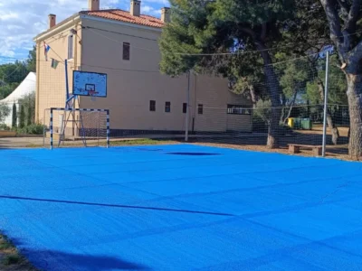 Svježe obojano plavo sportsko igralište sa zaštitnom mrežom u pozadini