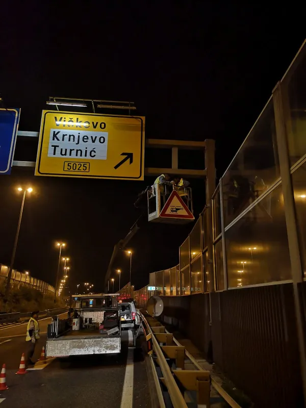 Terensko vozilo tvrtke s opremom za postavljanje prometnih znakova na noćnom gradilištu